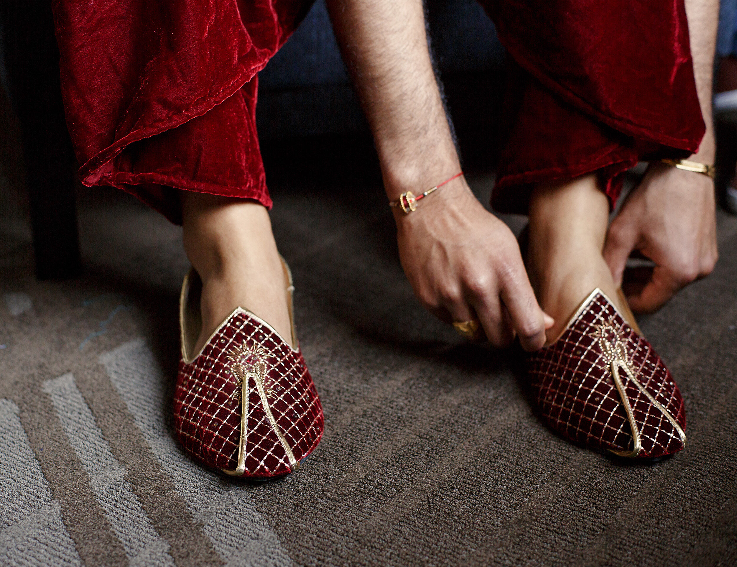 A groom in red traditional juttis for his wedding